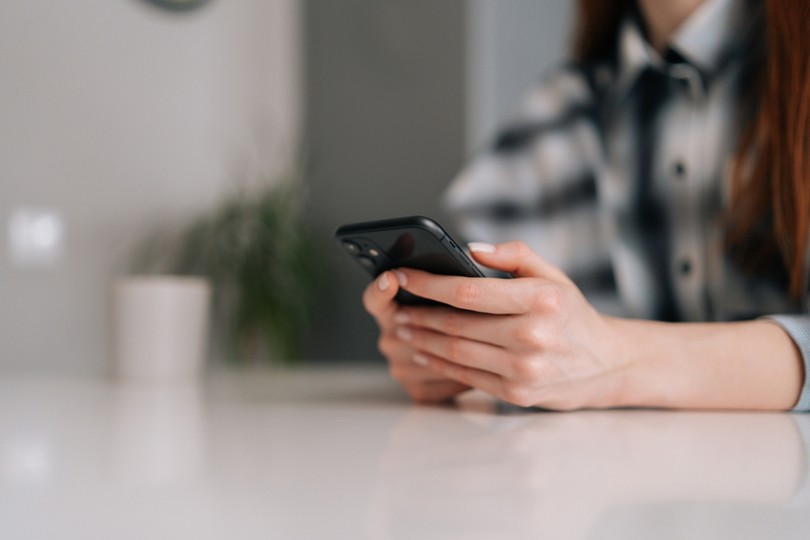 Hands of Woman in Check Shirt Using Phone