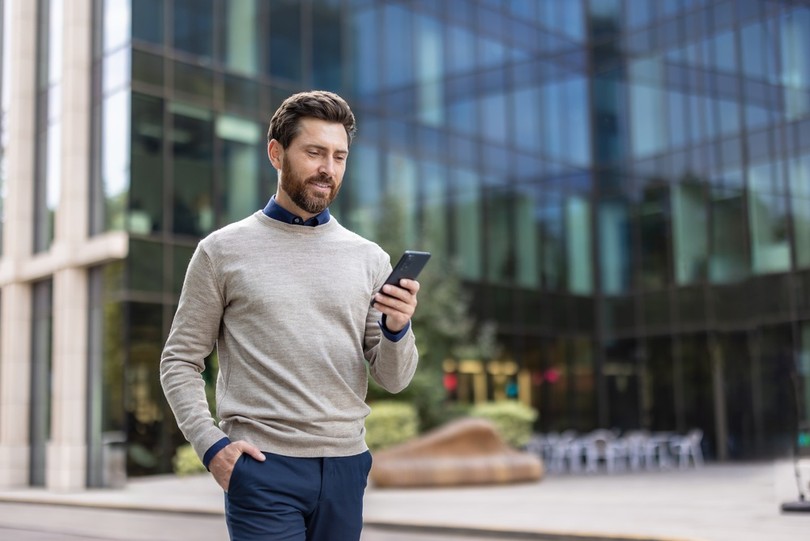 Smiling Man with Phone Outside Office Building
